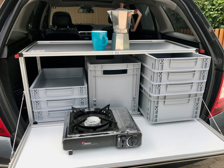 Heckklappe geöffnet: COMO Easy Campingbox mit offener Klappe, Kocher und Kaffeetasse
