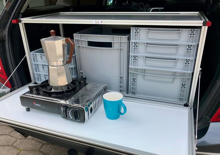 Heckklappe geöffnet: COMO Easy 55 Campingbox mit Blick auf Euroboxen, Kocher und Kaffeetasse